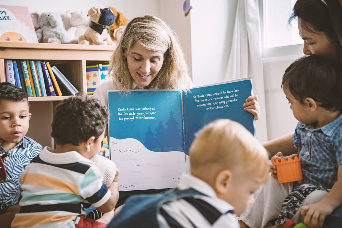 An educator reading with children gathered close